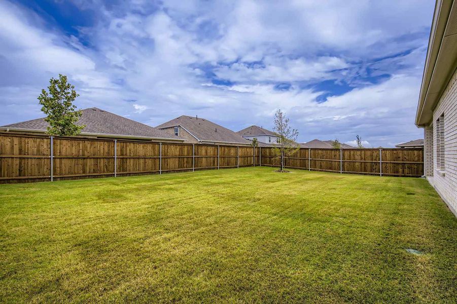 A fenced in yard with a house in the background.
