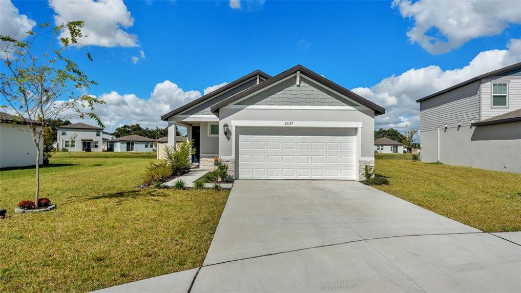 Front exterior of a new home in The Grove at Stuart Crossing - Premier Series, Bartow, FL, highlighting curb appeal (Image 22).