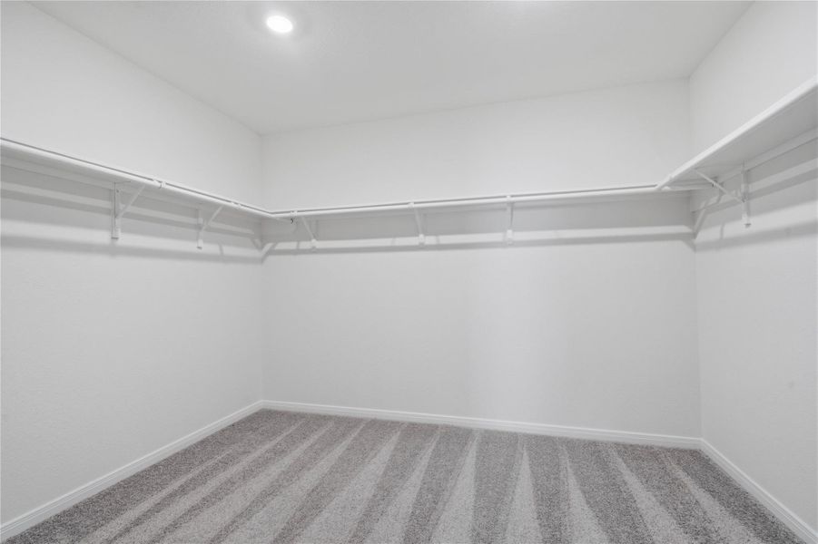 The spacious primary bedroom walk-in closet offers shelving, hanging rods, and ample storage space to keep your wardrobe organized.