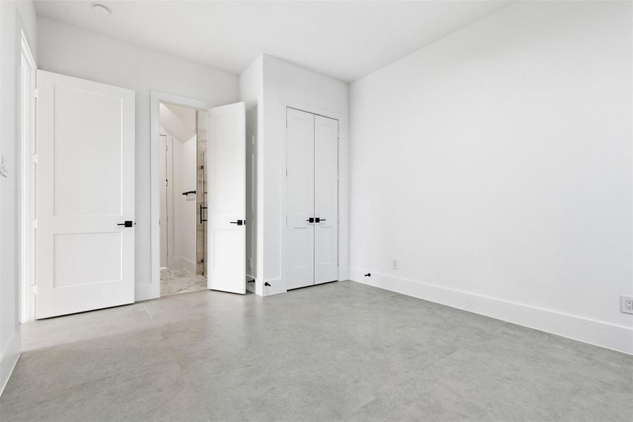 Dual closets and an ensuite bathroom entrance highlight the streamlined layout and modern hardware of the secondary suite.