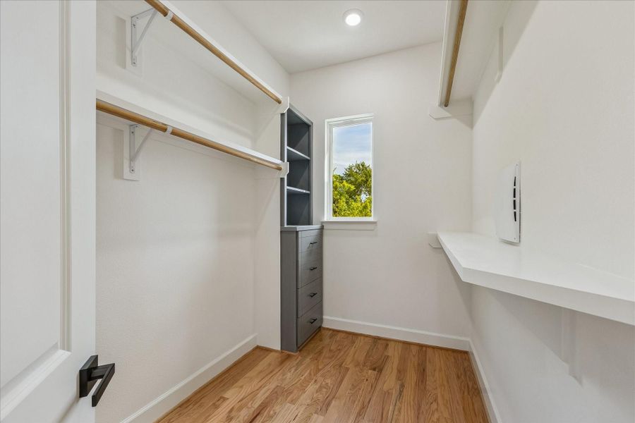 Luxurious primary bedroom closet featuring a window that bathes the space in natural light, complemented by built-in shelves and drawers for organized, elegant storage. This thoughtfully designed retreat combines functionality with refined style. Luxurious primary bedroom closet featuring a window that bathes the space in natural light, complemented by built-in shelves and drawers for organized, elegant storage. This thoughtfully designed retreat combines functionality with refined style.