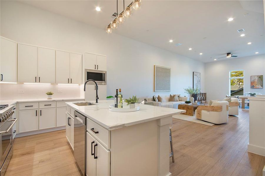 Kitchen with open floor plan, recessed lighting, light wood-style floors, stainless steel appliances, and white cabinets Kitchen with open floor plan, recessed lighting, light wood-style floors, stainless steel appliances, and white cabinets