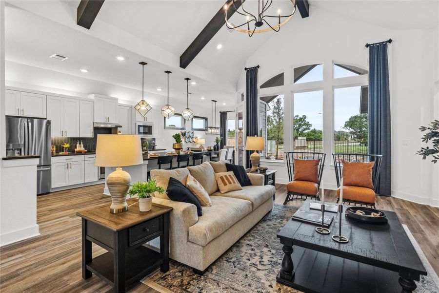 Living area with beam ceiling, wood finished floors, recessed lighting, a chandelier, and high vaulted ceiling