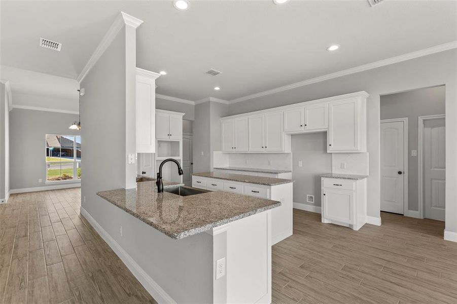 Kitchen with light hardwood / wood-style flooring, sink, kitchen peninsula, and white cabinets