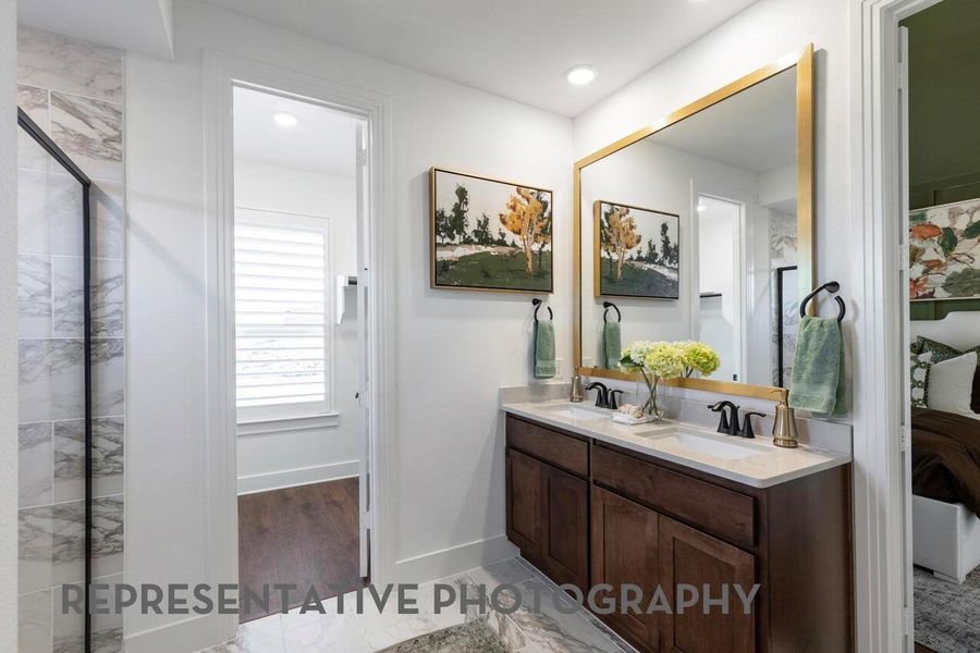 A primary bathroom with beautiful cabinetry, dual sinks, and a large mirror combines functionality and style for a bright, elegant space.