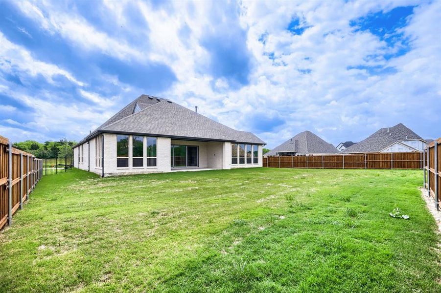 Rear view of house featuring a patio, a fenced backyard, brick siding, and a shingled roof