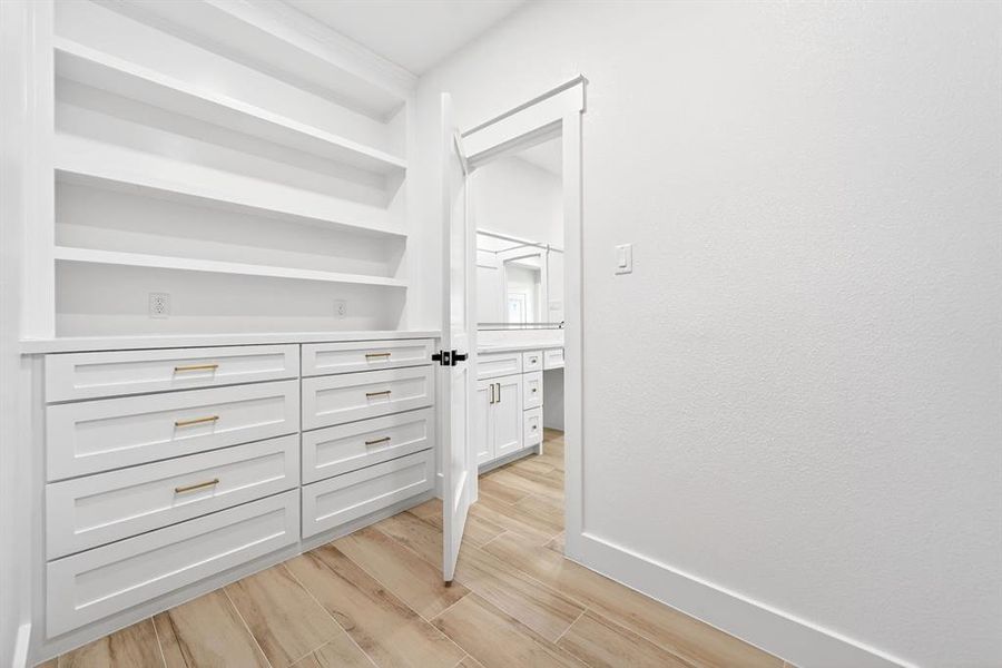 Built-in storage solutions featuring white cabinetry, gold-finish hardware, open shelving, and a durable countertop Built-in storage solutions featuring white cabinetry, gold-finish hardware, open shelving, and a durable countertop