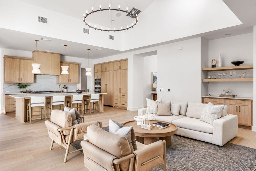 Living room featuring light wood finished floors, a high ceiling, and hanging lights