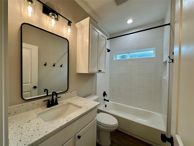 Full bath featuring vanity, shower / bathtub combination, and wood finished floors Full bath featuring vanity, shower / bathtub combination, and wood finished floors