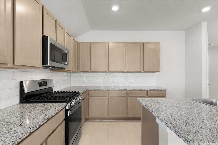 Kitchen with stainless steel appliances, light stone countertops, backsplash, recessed lighting, and light wood finish cabinetry