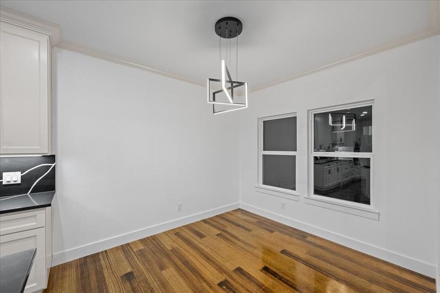 Unfurnished dining area featuring crown molding and dark wood-style floors