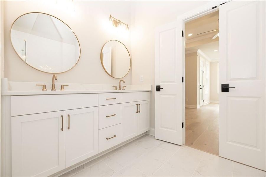 Primary bathroom has a double vanity with upgraded light fixtures and framed mirrors.  LIght and brigh spacw with high ceiling height:  bathroom can offer free- standing tubs and walk in showers or walk- thru shower.  Image is of a previously built Chamb