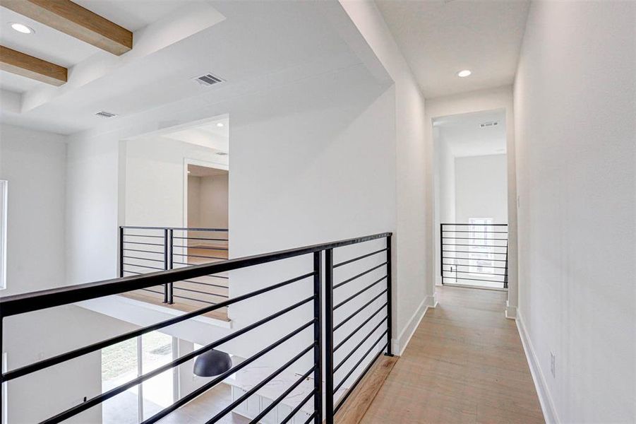 Hallway with light hardwood / wood-style floors and beam ceiling