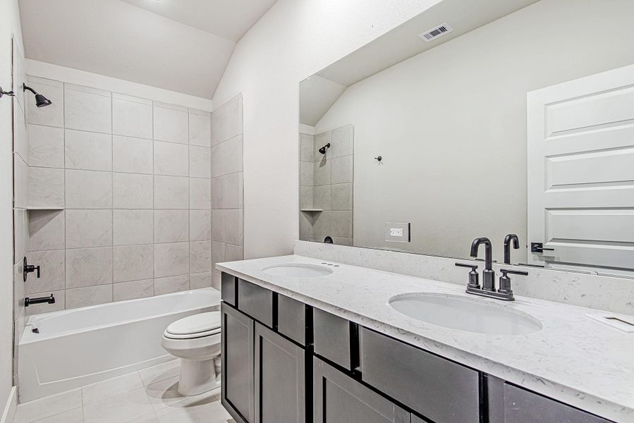 Stylish full bathroom with dual sinks, sleek matte black fixtures, a large mirror, and a beautifully tiled shower/tub combo.