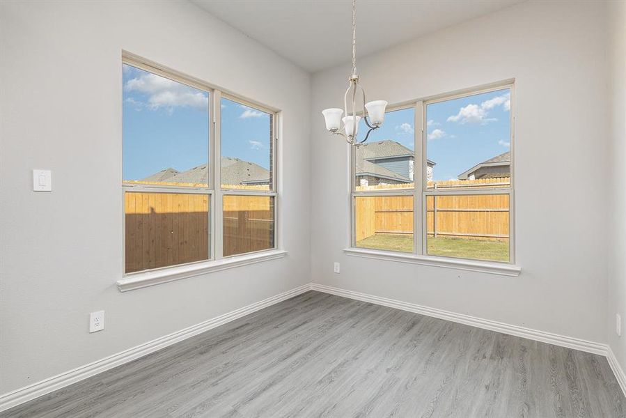 Unfurnished dining area featuring a wealth of natural light, an inviting chandelier, and hardwood / wood-style flooring