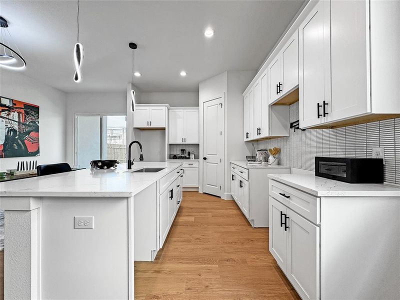 Kitchen with a sink, recessed lighting, backsplash, light wood finished floors, and white cabinetry