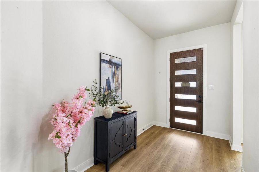 Entryway featuring wood-finish flooring and a contemporary dark wood entry door with horizontal frosted glass panes Entryway featuring wood-finish flooring and a contemporary dark wood entry door with horizontal frosted glass panes
