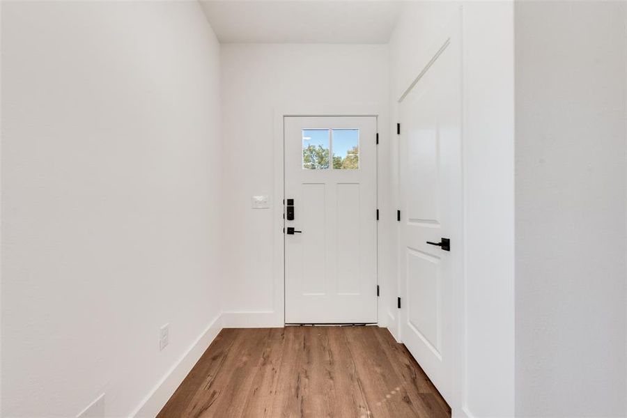 Doorway to outside with wood finished floors and baseboards Doorway to outside with wood finished floors and baseboards