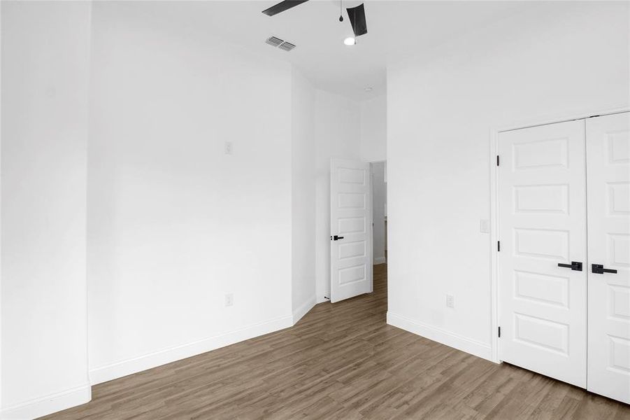 Unfurnished bedroom featuring wood finished floors, a ceiling fan, and a closet Unfurnished bedroom featuring wood finished floors, a ceiling fan, and a closet