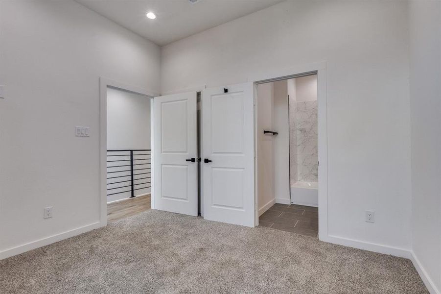 Unfurnished bedroom with light carpet, ensuite bath, and recessed lighting