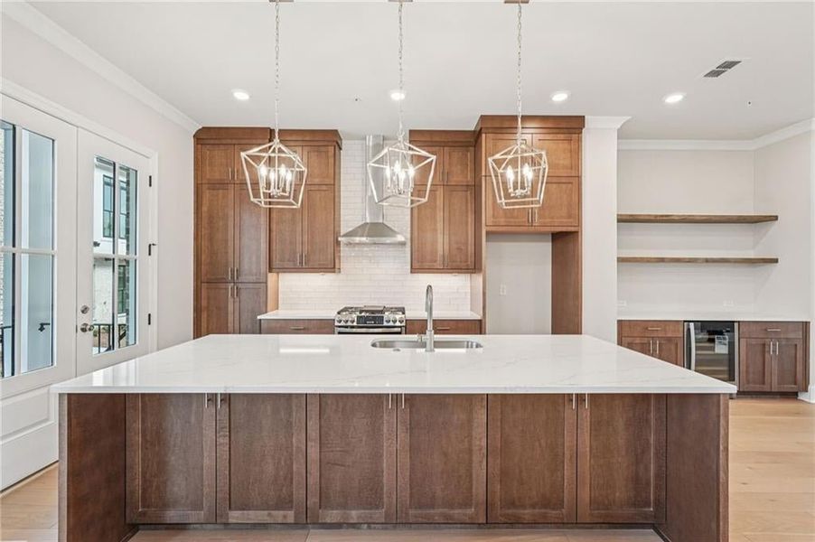 Kitchen with light wood-style floors, open shelves, light stone countertops, crown molding, and beverage cooler