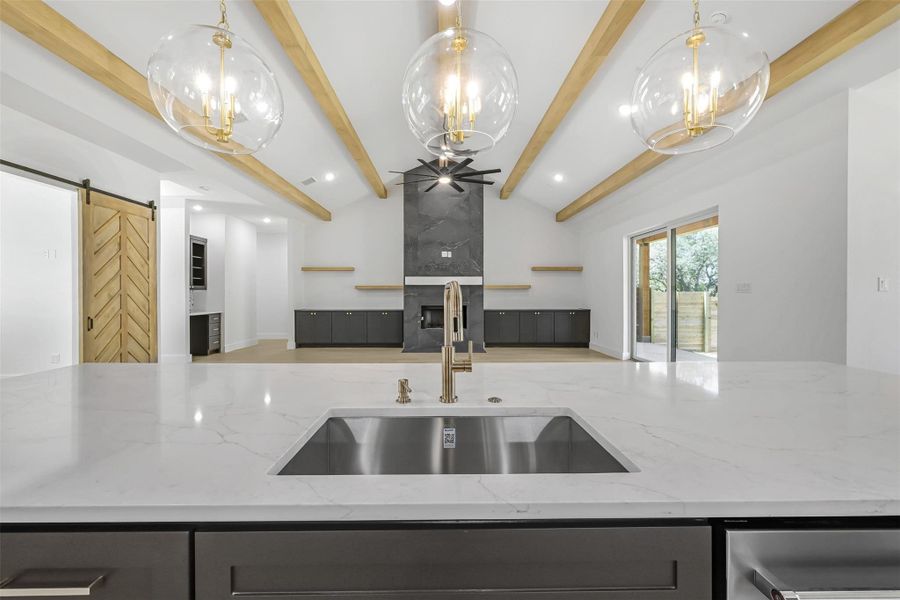 Kitchen with open floor plan, a barn door, light stone counters, a chandelier, and recessed lighting