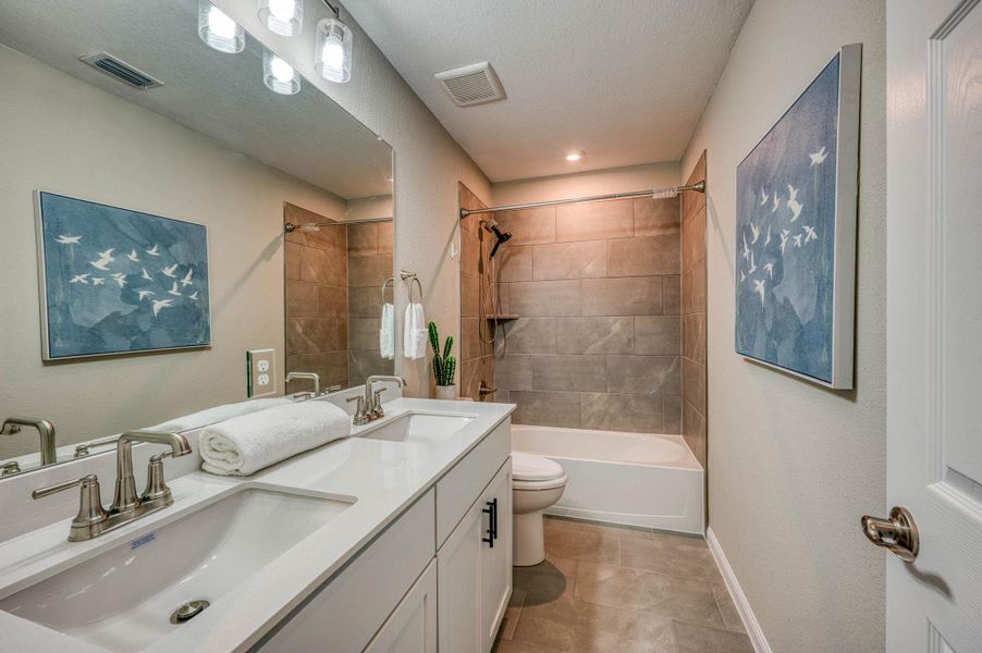 A spacious double vanity and a beautifully tiled tub shower highlight this contemporary bathroom. A spacious double vanity and a beautifully tiled tub shower highlight this contemporary bathroom.