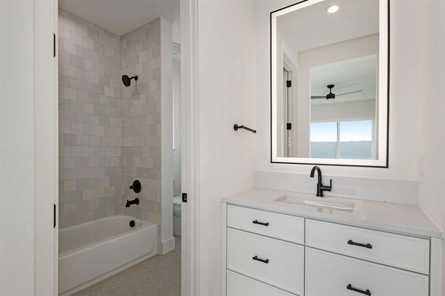 Full bathroom featuring ceiling fan, tiled shower / bath, vanity, toilet, and tile patterned flooring