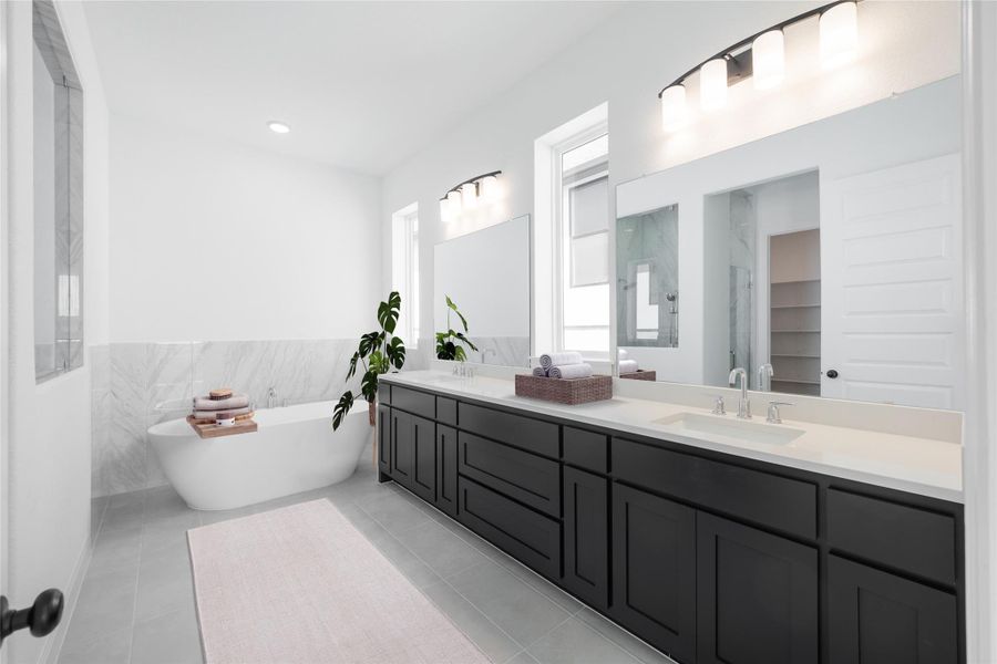 *Virtually Staged Primary Full bathroom with double vanity, a freestanding bath, tile walls, wainscoting, and light tile patterned floors