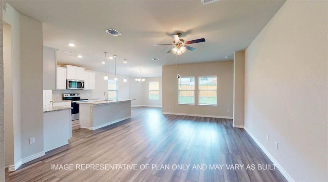 Kitchen featuring open floor plan, light wood-type flooring, appliances with stainless steel finishes, an island with sink, and pendant lighting Kitchen featuring open floor plan, light wood-type flooring, appliances with stainless steel finishes, an island with sink, and pendant lighting