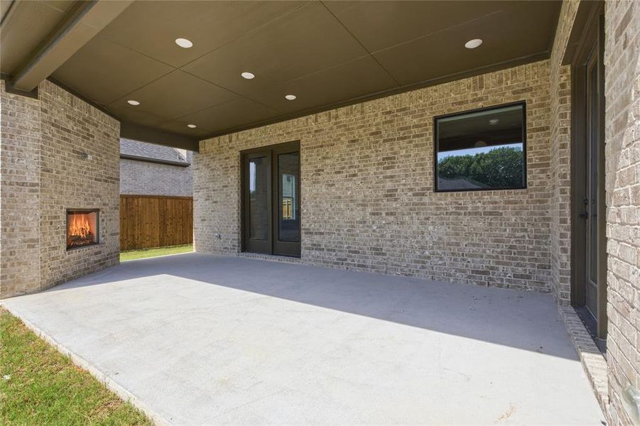 Covered patio featuring an outdoor fireplace, recessed lighting, brick exterior, and concrete flooring