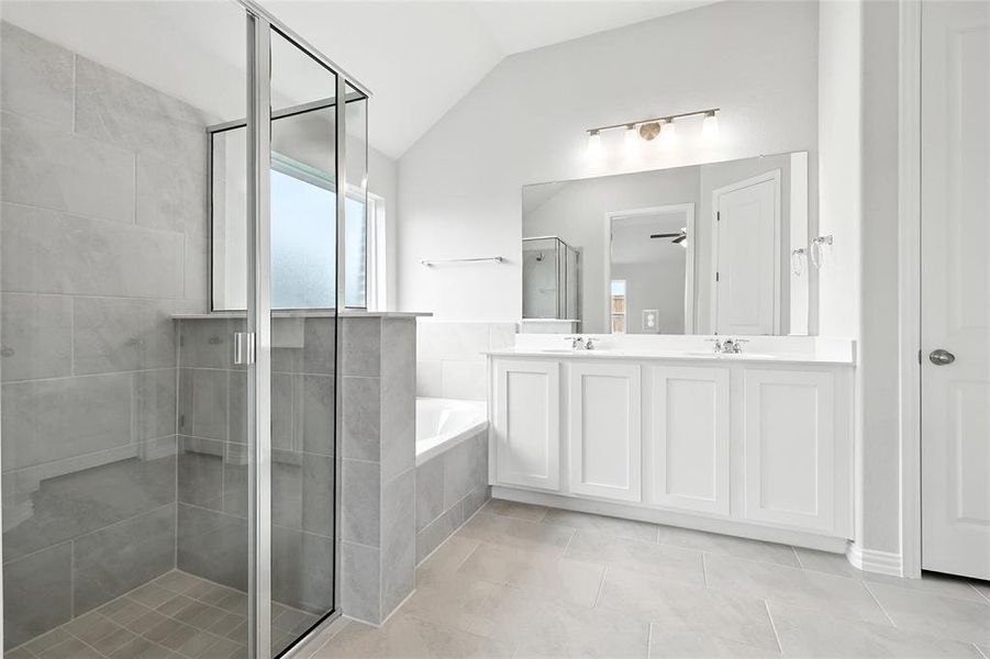 Bathroom with a shower stall, double vanity, a garden tub, vaulted ceiling, and tile patterned floors