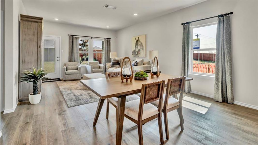 Open-concept living space featuring wood-finish flooring, recessed lighting, and a white paneled door with glass insert Open-concept living space featuring wood-finish flooring, recessed lighting, and a white paneled door with glass insert
