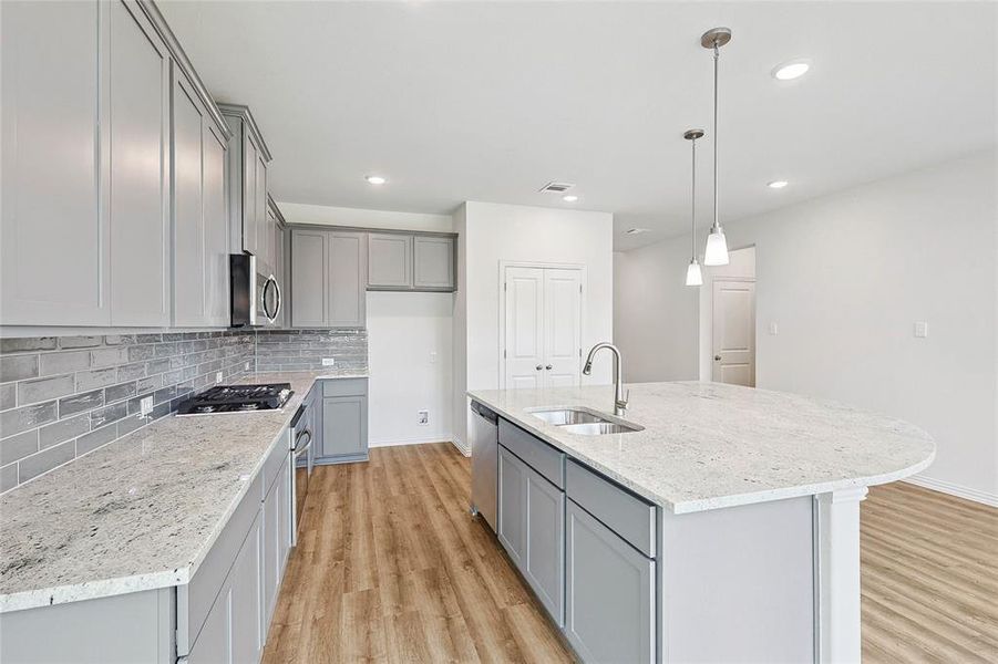 Kitchen with sink, gray cabinetry, a center island with sink, and light hardwood / wood-style flooring