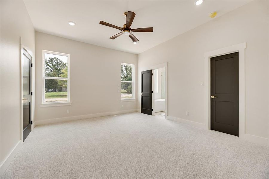 Unfurnished bedroom featuring ensuite bath, light colored carpet, a ceiling fan, and recessed lighting
