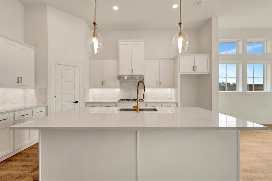 Spacious kitchen island with a light-toned countertop, complemented by white cabinetry and a herringbone-patterned backsplash
