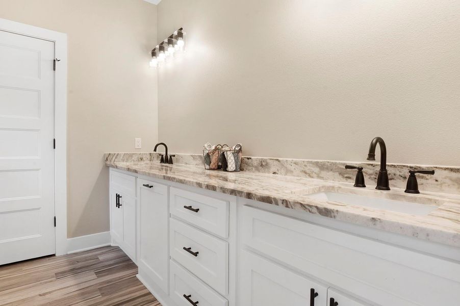 This photo showcases a modern bathroom with a double vanity featuring marble countertops and dark fixtures. The cabinetry is white with ample storage, and the lighting is stylishly contemporary, creating a bright and inviting space. This photo showcases a modern bathroom with a double vanity featuring marble countertops and dark fixtures. The cabinetry is white with ample storage, and the lighting is stylishly contemporary, creating a bright and inviting space.