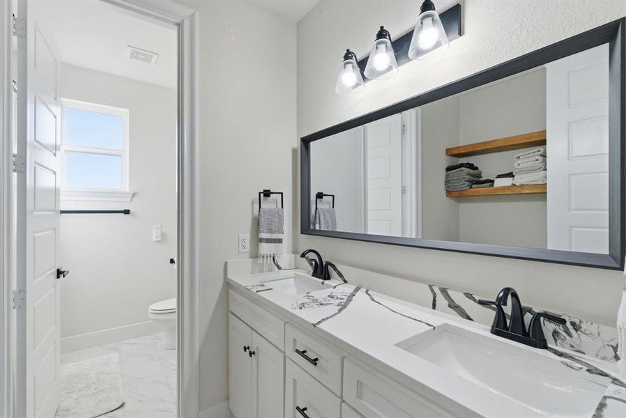 Full bath with double vanity and light marble finish flooring