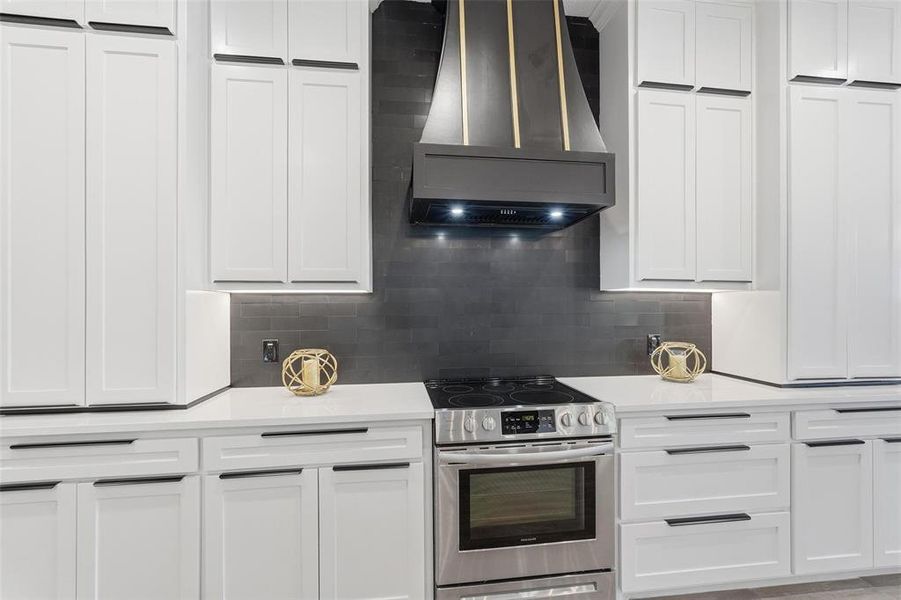 Kitchen featuring stainless steel electric range, wall chimney range hood, and white cabinets