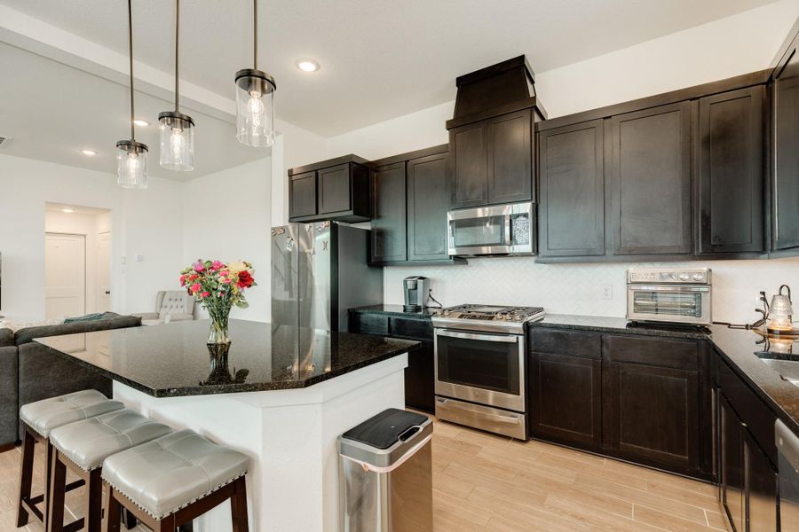 Island features a granite countertop and ample space for barstools, creating a functional breakfast bar.