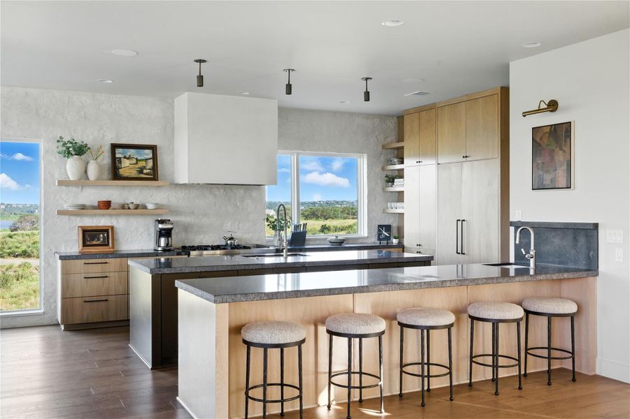 Kitchen featuring open shelves, a peninsula, a breakfast bar, dark wood-style flooring, and light brown cabinets