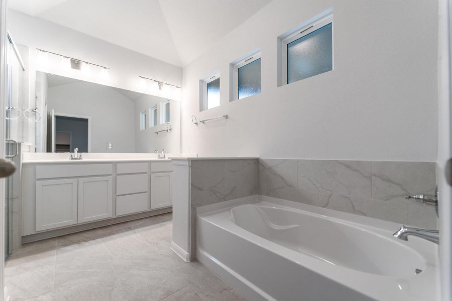 Bathroom with double vanity, vaulted ceiling, and a garden tub