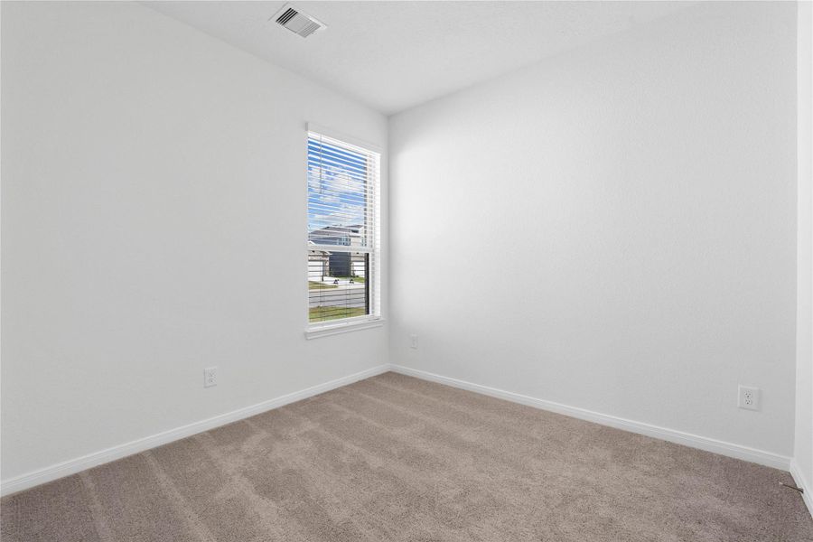 Tucked peacefully in the front of the home, this secondary bedroom offers comfort and style with plush carpeting, neutral paint tones, recessed lighting, a large window with blinds, and a generously sized closet Tucked peacefully in the front of the home, this secondary bedroom offers comfort and style with plush carpeting, neutral paint tones, recessed lighting, a large window with blinds, and a generously sized closet