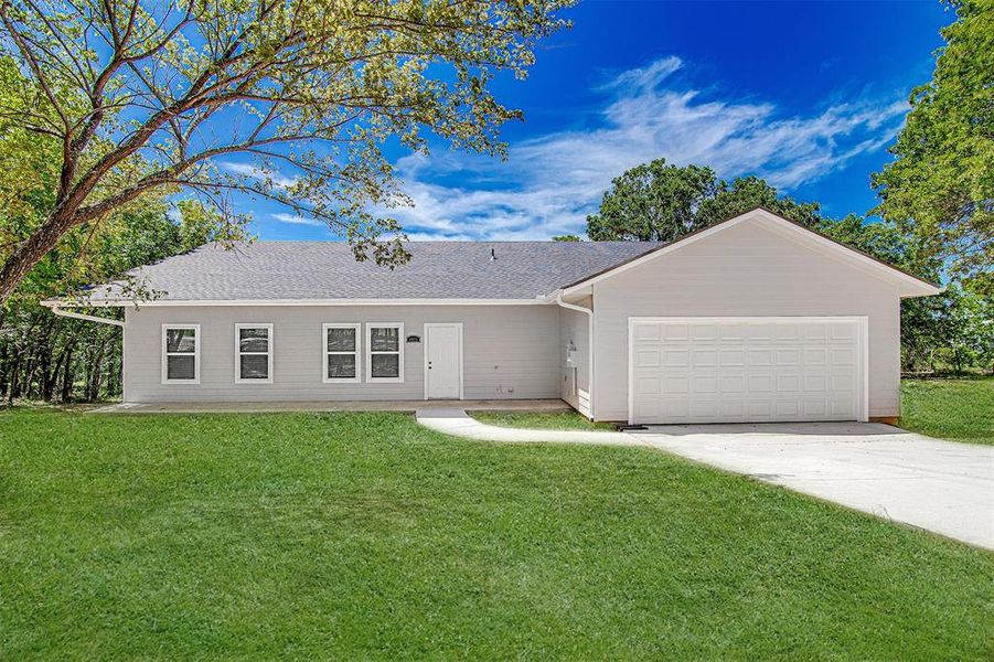 Ranch-style house featuring a garage and a front lawn