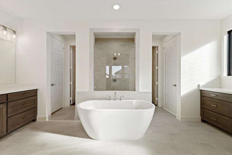 Full bath with vanity, a freestanding tub, a walk in shower, light tile patterned floors, and recessed lighting