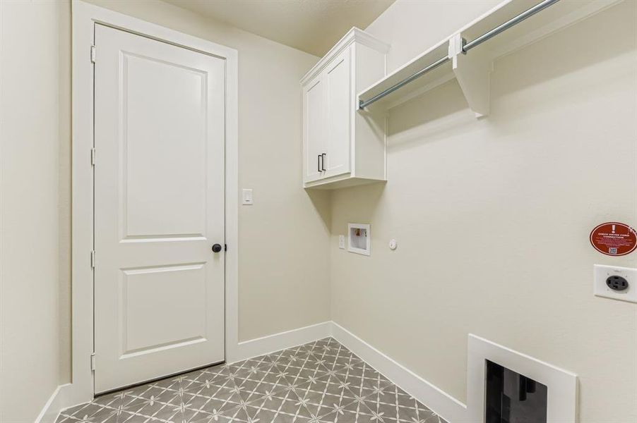 Laundry area with gas dryer hookup, washer hookup, hookup for an electric dryer, light tile patterned floors, and cabinet space