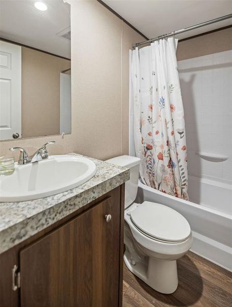 Full bathroom featuring a white porcelain sink, chrome faucet, wood-finish vanity with a stone-finish countertop, and a white toilet Full bathroom featuring a white porcelain sink, chrome faucet, wood-finish vanity with a stone-finish countertop, and a white toilet