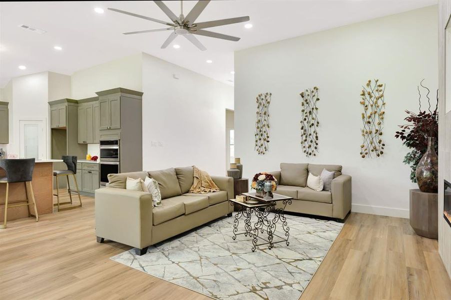 Open-concept living area featuring wood-finish flooring, recessed lighting, and a prominent ceiling fan Open-concept living area featuring wood-finish flooring, recessed lighting, and a prominent ceiling fan