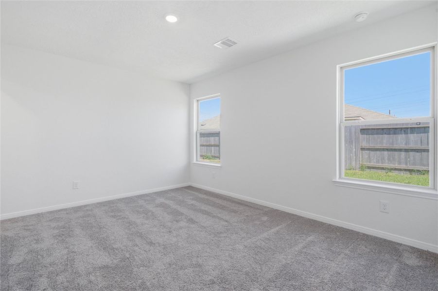 This move-in ready primary bathroom offers a spacious walk-in shower with built-in seat and tile surround, stained cabinetry topped with light countertops, dual sinks, high ceilings, neutral paint, a large mirror, and sleek, modern finishes for a polished look.
