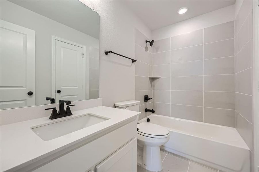 Full bathroom featuring tiled shower / bath, vanity, and toilet